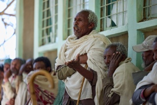 A village elder stands up to speak among a crowd which had gathered.