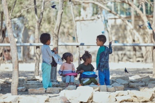 Children sitting outside at school eating food.