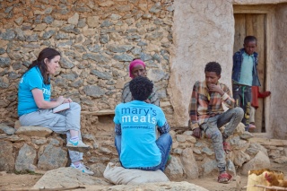 Mary's Meals members of staff in discussion with Letemariam and her grandson.