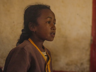Picture of a girl in school uniform pictured in looking away from the camera. 
